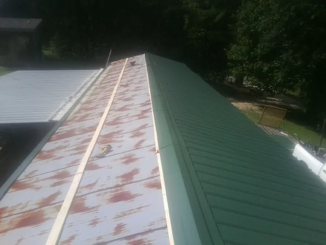 Old rusted panels beside newly installed green metal roofing — Wind Damage Roof Repair by Roofing Brothers in Madison