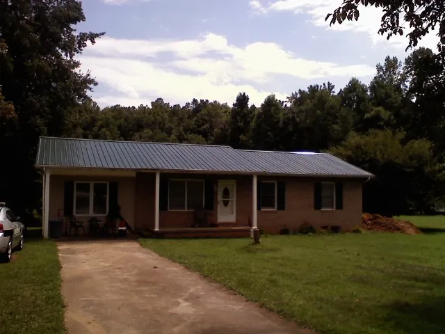 Dark green metal roof on a brick ranch with a covered porch in Madison